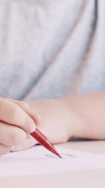 Dikey video. Sanatsal hobi. Çocukların yaratıcılığı. Dinlenme zamanı. Beyaz kağıda kurşun kalemle resim çizen tanınmayan küçük bir kız..