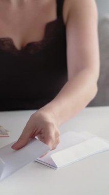 Dikey video. Tasarruf. Bütçe hesabı. Finansal zenginlik. Tanımlanamayan kadın zarftan nakit para sayıyor..