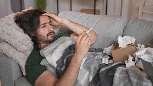 流感发烧 疾病的温度 疾病症状 在家里沙发上拿着温度计组织盒药丸的心烦意乱的病人 — 图库照片