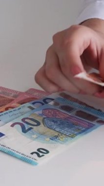 Dikey video. Tasarruf. Finansal kazanç. Maaş ödemesi. Bütçe ekonomisi. Avro nakit para banknotları sayan kadınların yakınlaşması.