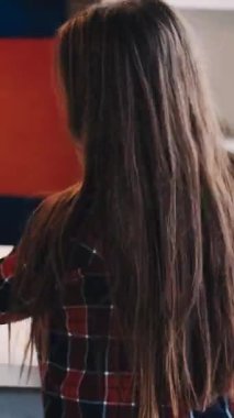 Dikey video. Sanat hobisi. Çocuklar resim yapıyor. Sanatsal aletler. Arkaya bakan küçük kız ışık odası iç dekorasyonu için renkli kalemler hazırlıyor..