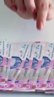 Dikey video. Tasarruf. Ukrayna Hryvnia enflasyonu. Finansal gelir. Kadın eli sayıyor 200 UAH Rhn kağıt para yığını.