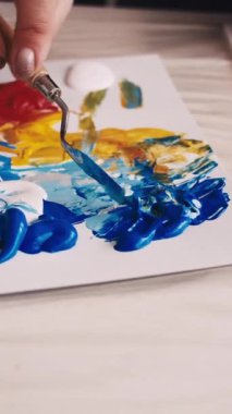 Dikey video. Sanat süreci. Kadın ressam. Resim okulunda. Resim odası yaratmak için spatulayla boyaları karıştıran tanınmamış bir kadın..
