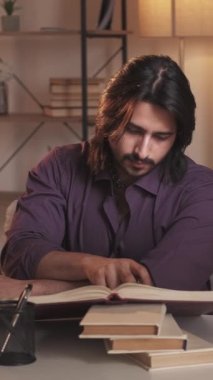 Dikey video. Kitap araştırması. Ev ödevi. Bilgi eğitimi için. Meraklı akıllı adam okumayı öğreniyor. İş yerinde sınava hazırlanıyor..