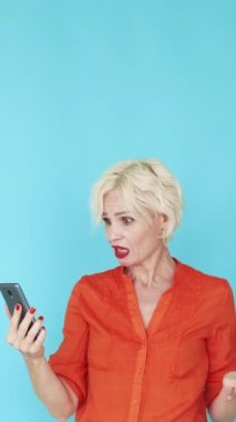 Dikey video. Çevrimiçi kavga. Münakaşa eden kadın. Sanal konferans. Surat asan öfkeli kadın elinde telefonla öfkeli bir şekilde maviye bağırıyor..