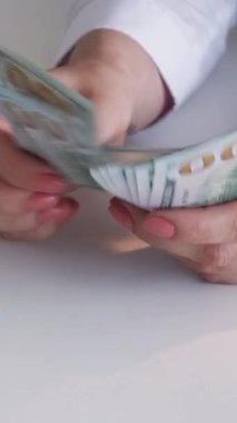 Dikey video. Tasarruf. Yabancı para birimi. Finansal bütçe. Avro nakit para yığını banknotlarından Amerikan dolarlarını sayan kadınların yakınlaşması.