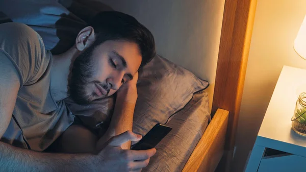 夜のチャット 不眠症だ オンライン通信 自宅の寝室でベッドでスマートフォンを使用してリラックスした男のテキストメッセージ読書メッセージ — ストック写真