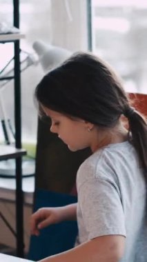 Dikey video. Sanatsal hobi. Yaratıcı kız. Resim okulunda. Dişi çocuk, hafif stüdyo içinde beyaz kağıda kalemle çizmeye başlıyor..