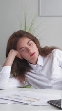 Dikey video. İnternetteki konferans. Sıkıcı kadın. Ofis işleri. Yorgun bayan dizüstü bilgisayarı arıyor, masa başında oturuyor, elini içeri sokuyor..