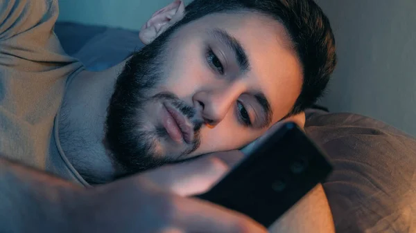 電話の夜 モバイルチャット インターネット不眠症 退屈疲れて落ち着きのない男使用してガジェットテキストメッセージスクロールフィードでベッドの後半でダークホームベッドルーム — ストック写真