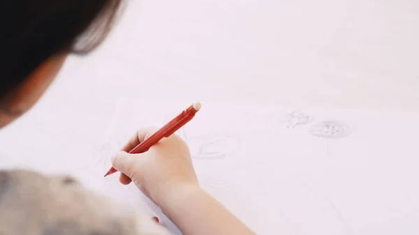 stock image Creative picture. Kids painting. Art hobby. Unrecognizable child drawing on white paper with pencil sitting table blurred.