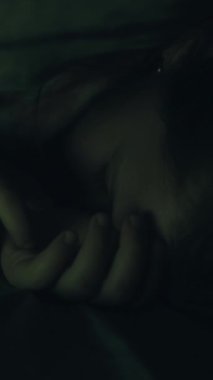 Dikey video. Çocukların huzursuz bir gece uykusu var. Karanlığın içinde kâbus gören rahatsız, yorgun küçük kız..