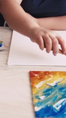 Dikey video. Sanat eseri yaratımı. Kadın ressam. Soyut resim. Tuvale spatula ve mavi boyayla resim yapan tanınmayan bir kadın..