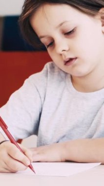 Dikey video. Çocuklar resim yapıyor. Sanat okulu. Yaratıcı zaman. Kağıt üzerine kalemle çizim yapan kız aydınlık odada oturuyor..