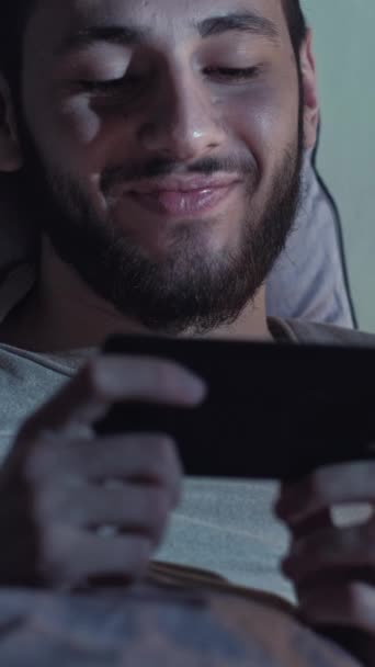 시간이야 온라인 커뮤니케이션 남자가 침대에서 까지웃으면서 카메라로 이야기하는 재미있는 대화를 — 비디오