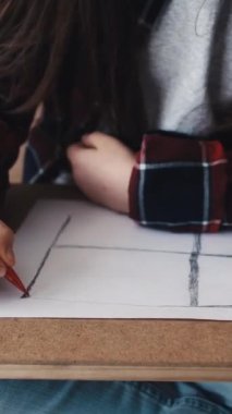 Dikey video. Çocukların yaratıcılığı. Ressam kız. İlham sanatı. Gülümseyen kadın pencere şeklini çiziyor. Işık stüdyosunun iç tarafında oturuyor..