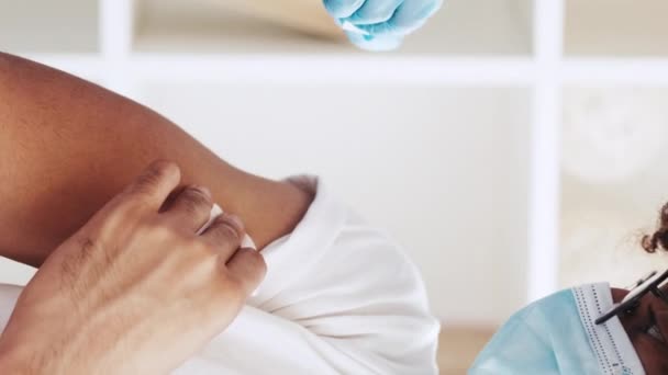 垂直录像 流感疫苗接种 疾病预防 免疫注射 男病人肩部注射后戴手套粘贴绷带的医生 — 图库视频影像