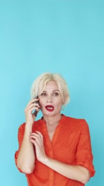 Dikey video. Sinir bozucu iletişim. Mutsuz kadın. Mobil bağlantı. Tatminsiz orta yaşlı bayan mavi poz veren çirkin biriyle akıllı telefon konuşuyor..