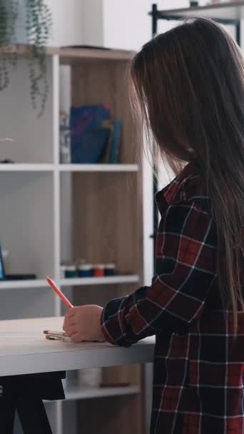垂直ビデオ 美術学校 子供の絵 芸術の授業 女の子は部屋のインテリアを描くためのカラフルな鉛筆でテーブルに座って — ストック動画