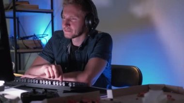 Uykucu oyuncu. Sıkıcı flama. Kulaklıklı yorgun bir adam evde bilgisayar başında oyun oynuyor klavyede yazıyor ve uykuya dalıyor..