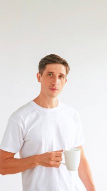 Sabah kahvesi. Kahvaltı içkisi. Yakışıklı sakin adam elinde fincanla beyaz fotokopi arka planında izole edilmiş içeceğin tadını çıkarıyor..
