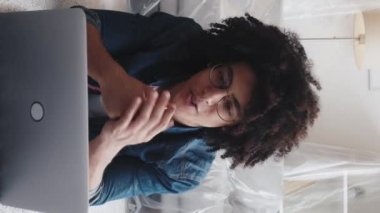 Dikey video çağrısı. Yeni evim. Sanal toplantı. Çevrimiçi taşınma. Mutlu adam el sallayarak selamlıyor. Düz bir defterde, üstü kapalı mobilyalarla konuşuyor..