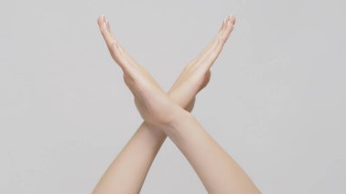 Protesto işareti. Dur sinyali. Kadın ellerini çapraz yapıp açık gri arka planda hareket ettiriyor..