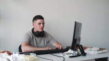 Bağımsız iletişim. Görüntülü arama. Gülümseyen adam barış işareti gösteriyor. Dağınık iş yerindeki monitöre merhaba işareti sallıyor..