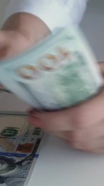 Dikey video. Para borcu. Banka kredisi. Finansal hesap. Kadın yöneticinin eli para sayıyor. 100 Amerikan doları..