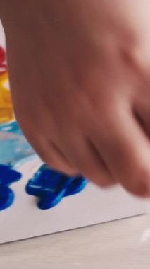 Dikey video. Resim okulunda. Sanat eseri yaratımı. Kadın ressam. Tanımlanamayan bir kadın, renkli spatula resimleriyle tuvalde soyut bir resim oluşturuyor..