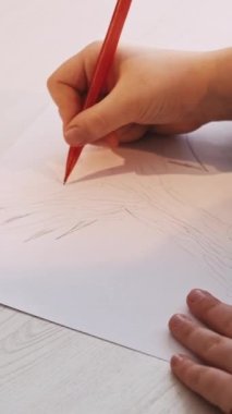 Dikey video. Çocukların yaratıcılığı. Çizen kız. Peri masalı sanatı. Tanımlanamayan küçük çocuk kalem ışığı odalı beyaz kağıda büyük bir ağaç çiziyor..