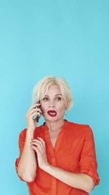 Dikey video. Sinir bozucu iletişim. Mutsuz kadın. Mobil bağlantı. Tatminsiz orta yaşlı bayan mavi poz veren çirkin biriyle akıllı telefon konuşuyor..