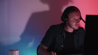 Serbest bir iş. Gece hacker 'ı. Uzaktan kumanda. Klavye kodlama yazılımında odaklanmış ciddi bir adam karanlık neon ışık odasında yeni bir program yaratıyor.