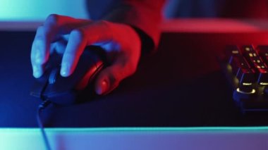 Gece oyunları. Serbest bir iş. Çevrimiçi eğlence. Erkek eller fareye tıklayarak sorunsuz döngü seçerek karanlık neon ışıklı odada oynuyor.