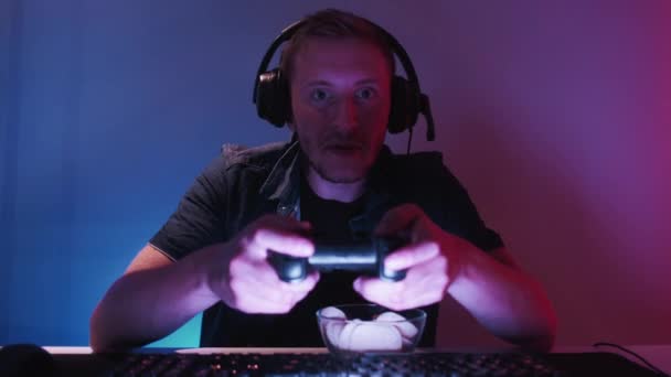 ホームゲーム プロ選手 サイバースポーツ大会 興奮男ゲーマー遊びます食べるスナックチップで夜に使用して現代的なコンソールにコンピュータで夜 — ストック動画