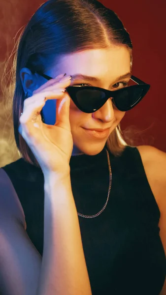 アイウェアのファッション 光学アクセサリー 笑顔女性取るオフサングラス見た目Insidious式で青ネオンライトオン赤 — ストック写真