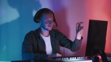 Gece yayını. Barış jesti. Selamlama işareti. Tatmin olmuş yetişkin erkek oyuncu V işaretsiz döngü gösteriyor. Monitöre bakıyor, oyun oynuyor. Karanlık ışıkta takım arkadaşlarıyla iletişim kuruyor..