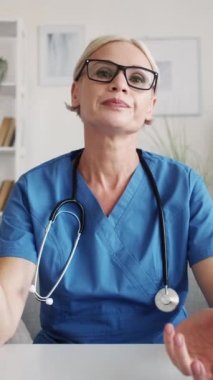 Dikey video. Çevrimiçi toplantı. Şüpheci kadın doktor. Gözlüklü cahil kadın, masa lambasının iç tarafında oturan meslektaşıyla aynı fikirde değildi..