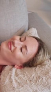 Dikey video. Gün rahatla. Dinlenmenin tadını çıkarıyorum. Tatmin olmuş bir bayan kanepede uzanıyor. Haftasonu uyanıyor. Haftasonu uyanıyor..