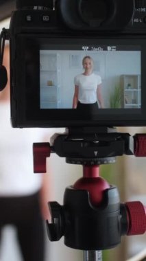 Dikey video. Fitness etkileyicisi. Spor blogu. Atletik kadın el kaydı için egzersiz yapıyor. Işık odasının içinde kamera önünde içerik çekimleri yapıyor..