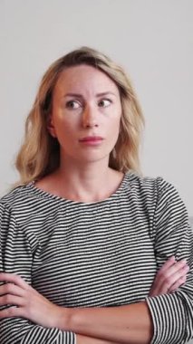 Dikey video. Hoşnutsuz bir durum. Şüpheci kadın. Belirsiz bir seçim. Süpheli, suratını buruşturan kadın göğsünü açıp, iç mekânda oturuyor..