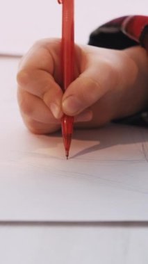 Dikey video. Çizen çocuk. Sanatsal hobi. Yaratıcı zaman. Tanımlanamayan küçük çocuk beyaz kağıt üzerinde kalem oturma masası ile ağaç yapıyor..