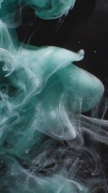 Dikey video. Duman sıçrıyor. Suyu boya. Su altı dalgası. Siyah soyut sanat arka planında Teal mavisi renkli simli parçacıklar buhar bulutu hareketi.