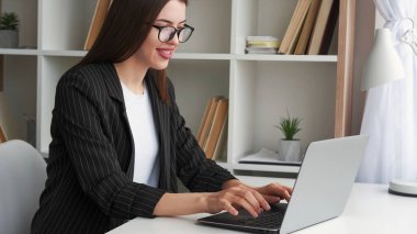 İnternet işi. Uzaktan kumanda. İnternet pazarlaması. Ev işyerinde dizüstü bilgisayar kullanan başarılı gülümseyen kadın makale yazıyor..