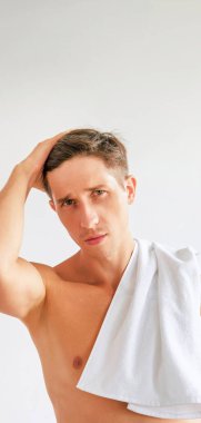 Saç bakım prosedürleri. Günlük rutin. Yakışıklı, kendine güveni olmayan, sabah duşundan sonra havlusu olan beyaz fotokopi çekilen arka planda yalnız bir adam..