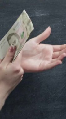 Dikey video. Para hareketi. Finansal kriz. Kopya alanı karatahtasında Hryvnia destesiyle kadın el çırpması.