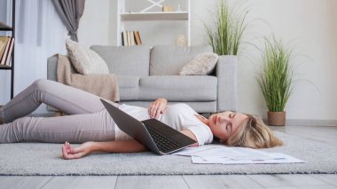 Çok çalışan serbest çalışan biri. İnternet işi. Yorgun kadın yönetici dizüstü bilgisayarlı kağıt grafiklerle yerde uyuyakalıyor. İç mekanda dinlenirken yorgunluk hissediyor..