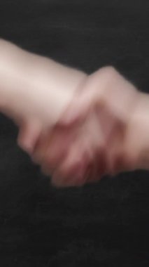 Dikey video. Meslektaşların tokalaşması. Cinsiyet eşitliği. Erkek ve kadın, siyah tahtada 3 adet jest şablonu ile el sıkışıyor..