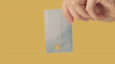 Dikey video. Para transferi. Nakit ödeme. Sarı arka planda dolarları olan el yiyen bir kadın..