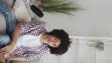 Dikey video. Telefon açılıyor. Teknik video günlüğü. Elektronik inceleme. Neşeli blogcu adam modern ev stüdyosunun içinde mikrofona konuşan alet kayıt içeriğini açıyor..